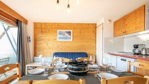 Ein Essbereich mit einer Holzwand, einer blauen Sitzbank und einer Küche im Hintergrund.