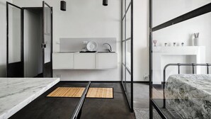 A modern bedroom with a bed, a small bedside table, a white dresser, and a glass shower enclosure. - Minimal Chic Studio near Milan Centrale (Milan)
