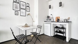 A compact kitchen with a white countertop, a black metal shelf, and a microwave. - Minimal Chic Studio near Milan Centrale (Milan)
