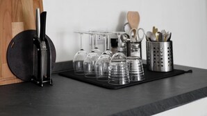 A kitchen counter with a cutting board, knife, wine glasses, and utensils. - Minimal Chic Studio near Milan Centrale (Milan)