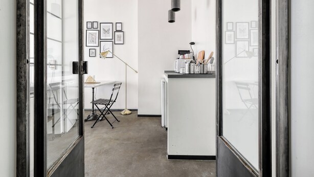 A modern kitchen with a central island, a dining area with a chair, and a wall adorned with framed pictures. - Minimal Chic Studio near Milan Centrale (Milan)