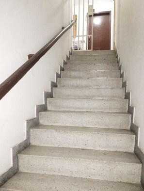 A staircase with a metal handrail leading to a door at the top.