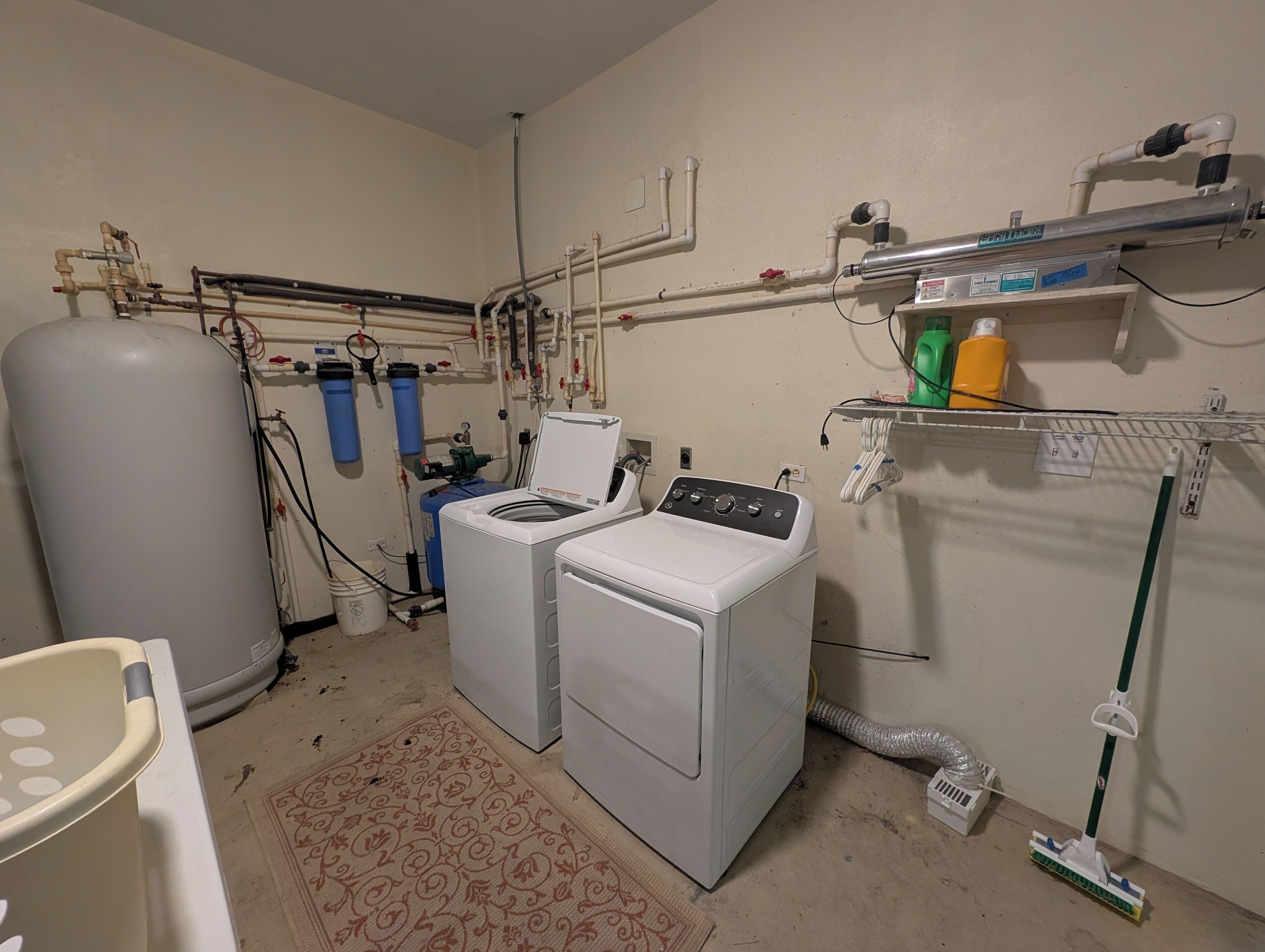 Een wasserette met twee wasmachines, een grote boiler en diverse leidingen en slangen.