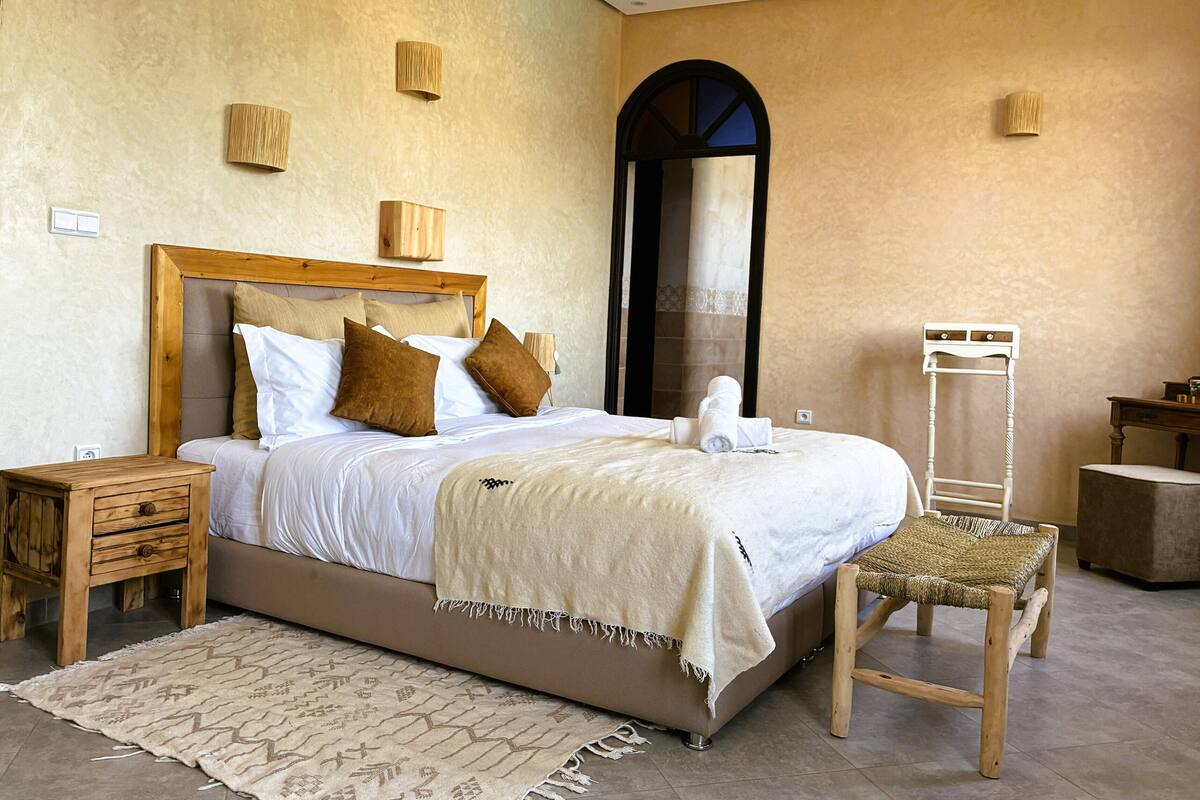 A bedroom with a bed, bedside tables, a chair, a mirror, and a small table.
