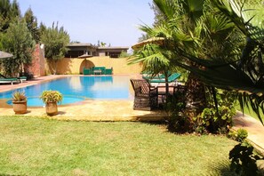 A swimming pool with lounge chairs and potted plants.