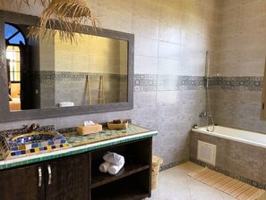 A bathroom with a tiled floor, a sink with a mosaic countertop, a bathtub, and a shower.
