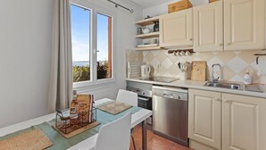 A kitchen with a dining table, chairs, a window, cabinets, and kitchen appliances.