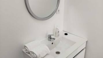 A modern bathroom with a white sink, a round mirror, and a towel on the counter.