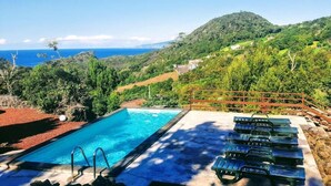 Una piscina con vista sull'oceano e sulle colline.