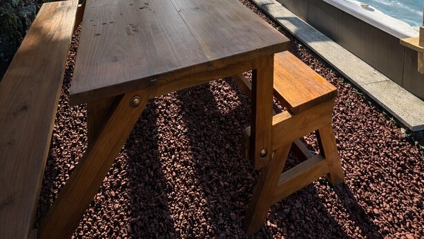 Un tavolo e una panca di legno in giardino, con una vasca idromassaggio e una porta vetrata che dà su una stanza.