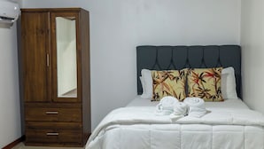 A bedroom with a bed, a wooden wardrobe, and a mirror.
