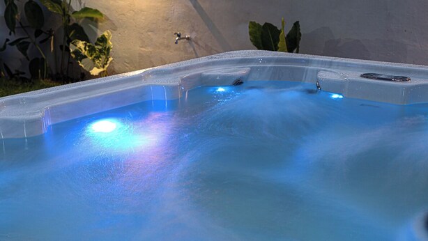 A hot tub with a blue light, surrounded by plants.