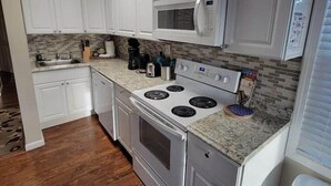 A kitchen with white cabinets, a microwave, a stove, and a sink. - Grand View | Walk to Falls, Casino & Attractions (Niagara Falls)