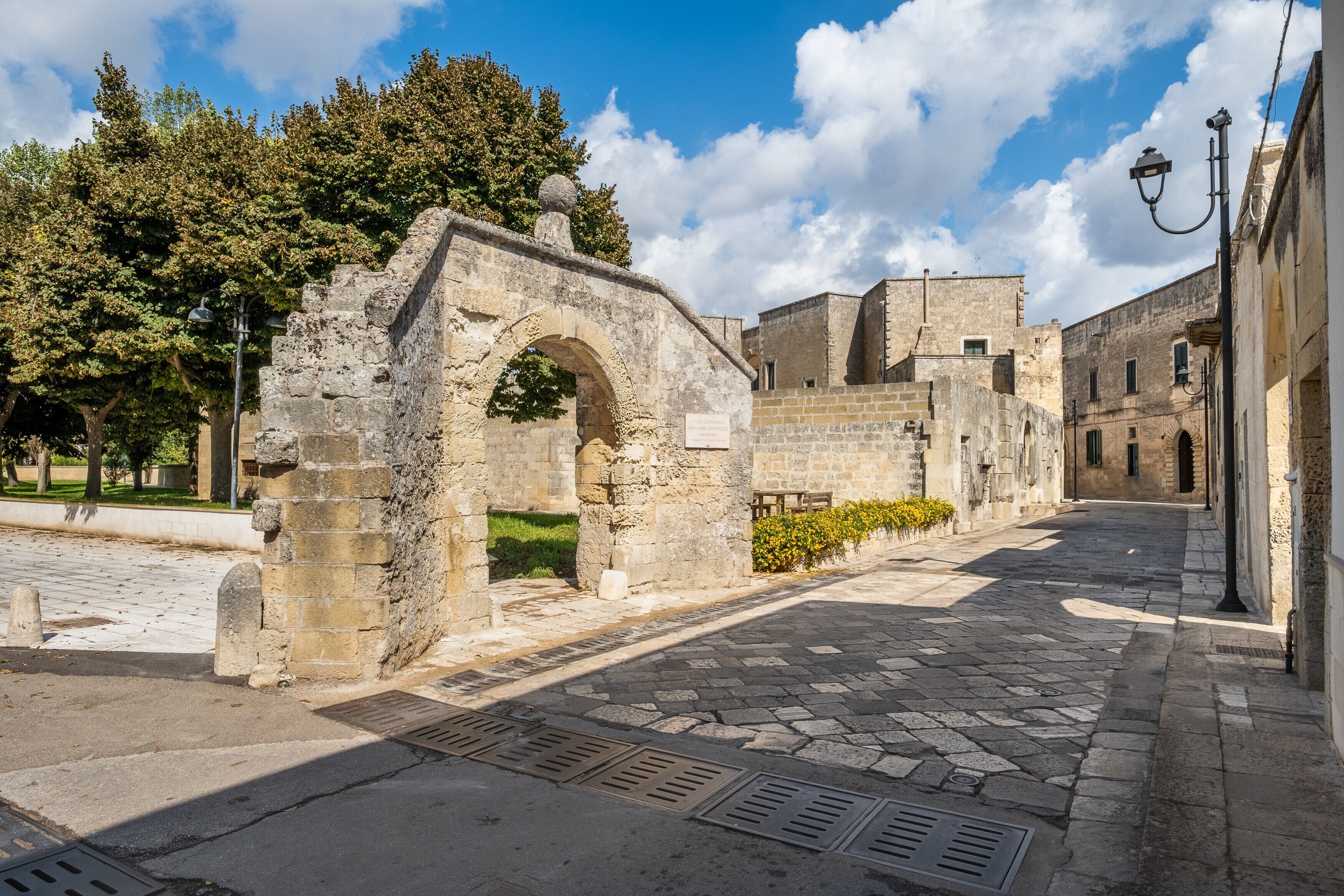 Ein gepflasterter Weg führt zu einem Bogenportal, das von Gebäuden mit traditioneller Architektur gesäumt wird.