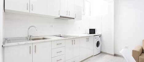 A modern kitchen with white cabinets, a stainless steel sink, and a built-in washing machine.