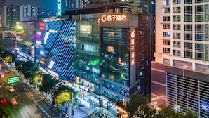 A modern building with illuminated signage and a glass facade, surrounded by a busy urban street at night. - Orange Hotel Guangzhou Tianhe Sports Center (Guangzhou)