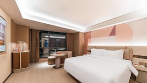 A modern hotel room with a large bed, a small round table, a sofa, and a desk with a lamp. - Orange Hotel Guangzhou Tianhe Sports Center (Guangzhou)