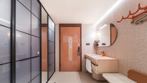 A modern bathroom with a glass partition, a sink with a mirror, and a bench. - Orange Hotel Guangzhou Tianhe Sports Center (Guangzhou)