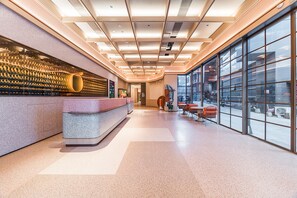 A modern reception area with a counter, seating, and large windows. - Orange Hotel Guangzhou Tianhe Sports Center (Guangzhou)