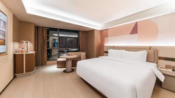 Una habitación de hotel moderna con una cama grande, una mesita redonda pequeña, un sofá y un escritorio con una lámpara.