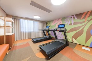 A fitness room with treadmills, a desk, and a chair. - Orange Hotel Guangzhou Tianhe Sports Center (Guangzhou)