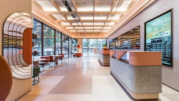 Un moderno vestíbulo de hotel con mostrador de recepción, zona de estar y grandes ventanales que ofrecen vistas al exterior.