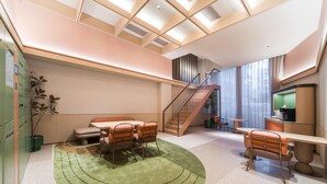 A modern interior with a staircase, a dining area with a green rug, and a seating area with orange chairs. - Orange Hotel Guangzhou Tianhe Sports Center (Guangzhou)