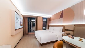 A hotel room with a bed, a desk, and a chair. There is a window with curtains and a view of the outside. - Orange Hotel Guangzhou Tianhe Sports Center (Guangzhou)