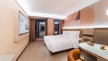 A hotel room with a bed, a desk, and a chair. There is a window with curtains and a view of the outside.
