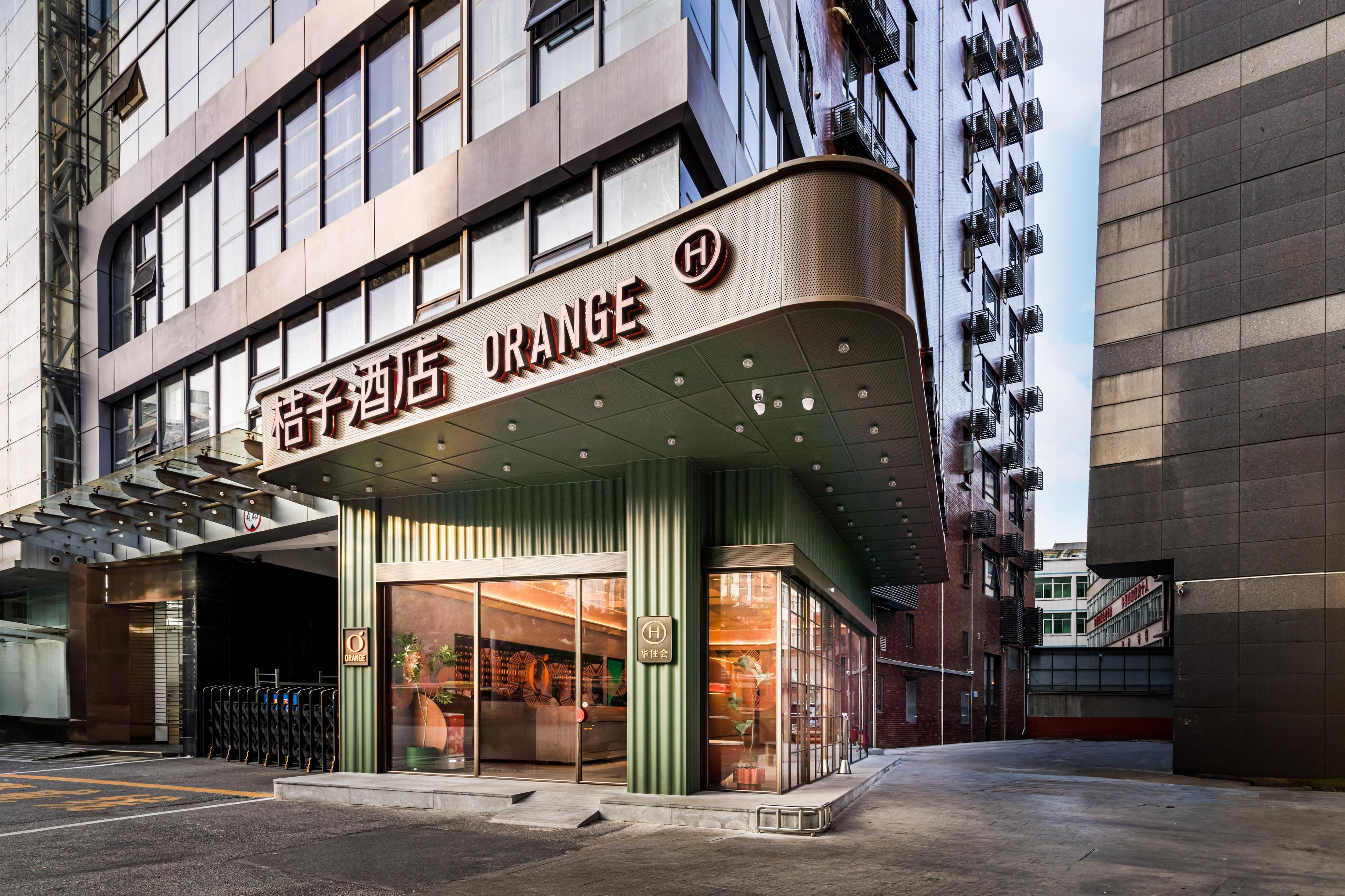 L’entrée d’un hôtel au design moderne, caractérisée par une façade incurvée et une enseigne bien visible.
