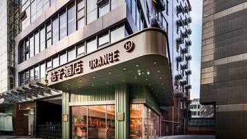 Entrada de hotel com design moderno, destacando uma fachada curva e uma placa bem visível.