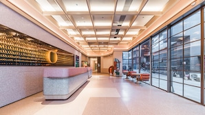 A modern reception area with a counter, seating, and large windows. - Orange Hotel Guangzhou Tianhe Sports Center (Guangzhou)