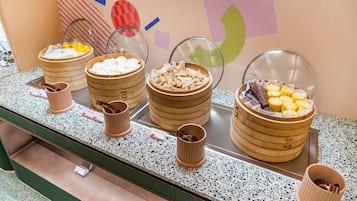 Mostrador de buffet con diversos alimentos en recipientes de garmet.