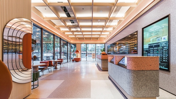 A modern hotel lobby with a reception desk, seating area, and large windows offering views of the outdoors. - Orange Hotel Guangzhou Tianhe Sports Center (Guangzhou)