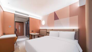 Una habitación de hotel moderna con una cama grande, un escritorio y una pequeña mesa.