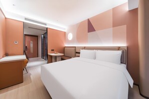 A modern hotel room with a large bed, a desk, and a small table. - Orange Hotel Guangzhou Tianhe Sports Center (Guangzhou)
