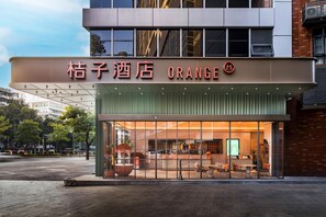 A hotel with a modern facade, large glass windows, and a prominent orange sign. - Orange Hotel Guangzhou Tianhe Sports Center (Guangzhou)