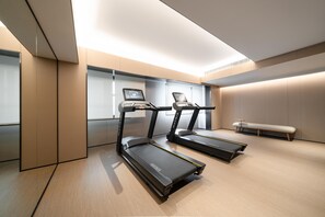 A modern gym with two treadmills, a bench, and a digital display on the wall. - Ji Hotel Guangzhou Sanyuanli Medicine University (Guangzhou)