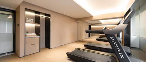 A modern hotel room with a treadmill, a minibar, and a mirror.