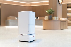 A modern hotel lobby with a reception desk, a large white air purifier, and a clock on the wall. - Ji Hotel Guangzhou Sanyuanli Medicine University (Guangzhou)
