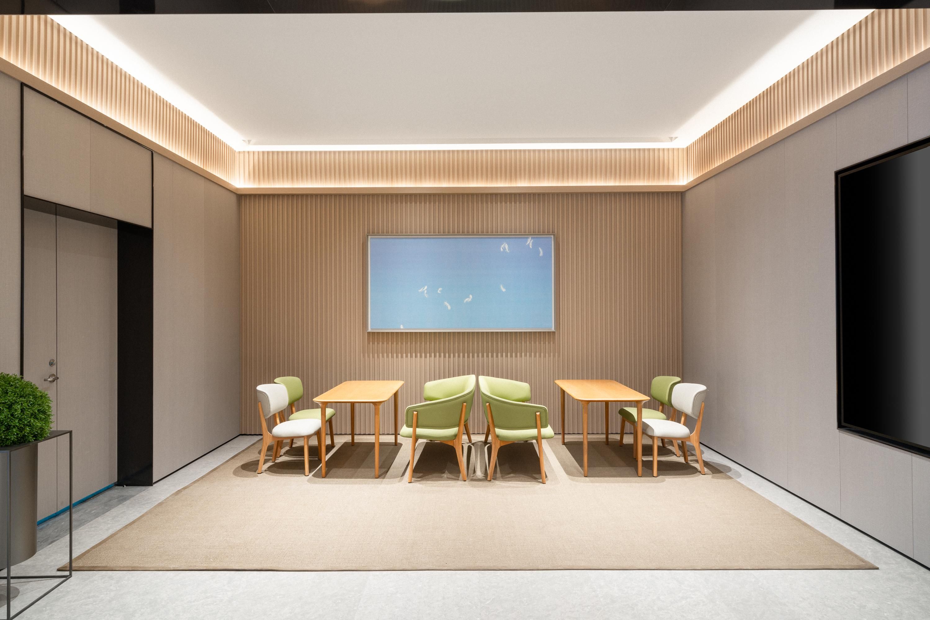Uma sala de conferências moderna com uma grande TV de tela plana, mesas de madeira e cadeiras verdes.