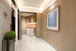A modern hallway with a minimalist design, featuring a framed artwork on the wall, a potted plant, and a clean, polished floor. - Ji Hotel Guangzhou Sanyuanli Medicine University (Guangzhou)