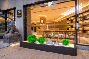 A hotel entrance with a lion statue, a reception area with a modern interior, and a seating area visible through the glass facade. - Ji Hotel Guangzhou Sanyuanli Medicine University (Guangzhou)
