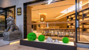 A hotel entrance with a lion statue, a reception area with a modern interior, and a seating area visible through the glass facade. - Ji Hotel Guangzhou Sanyuanli Medicine University (Guangzhou)