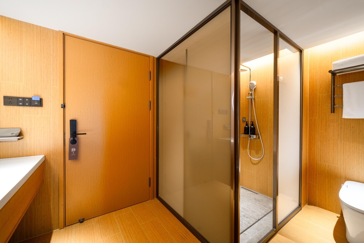 A modern bathroom with a wooden vanity, a glass shower enclosure, and a toilet.