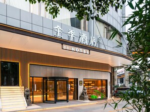 A hotel entrance with a modern design, featuring a prominent sign, a lion statue, and a staircase leading to the entrance. - Ji Hotel Guangzhou Sanyuanli Medicine University (Guangzhou)