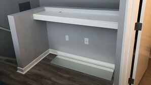 A room with a built-in white shelf unit against a grey wall, a door with a black handle, and a wooden floor.