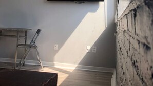 A room with a mounted TV, a ladder, and a wooden floor.