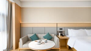 Een moderne hotelkamer met een bed, een slaapbank, een klein tafeltje en een nachtkastje.