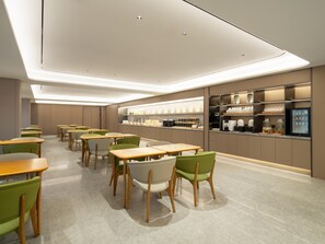 A modern dining area with tables and chairs, a kitchen counter with appliances, and a television screen. - Ji Guangzhou Baiyun Intern Conference Center Qifu (Guangzhou)